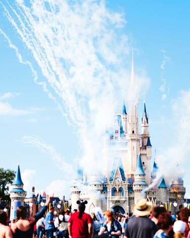 Cinderella's Castle at Walt Disney World with fireworks and crowds on a bright day