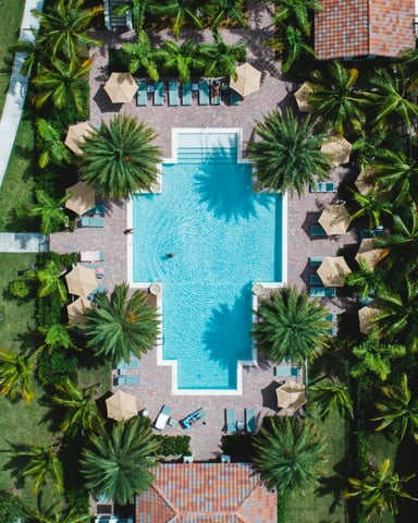 Aerial view of a Florida resort community pool surrounded by palm trees and sun loungers