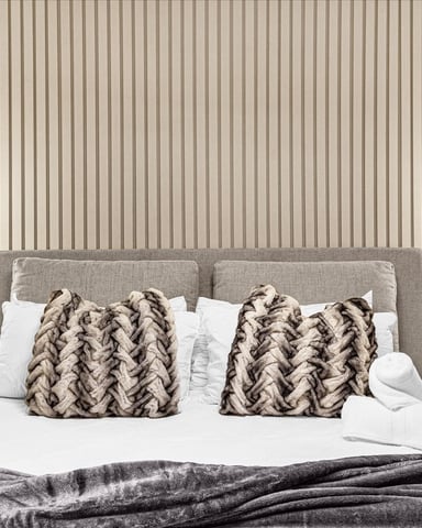 Modern bedroom with gray upholstered headboard, white bedding, patterned throw pillows, wood nightstands, and neon pendant lights
