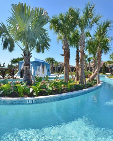 Lazy river with turquoise water winding through palm trees and tropical landscaping at resort community