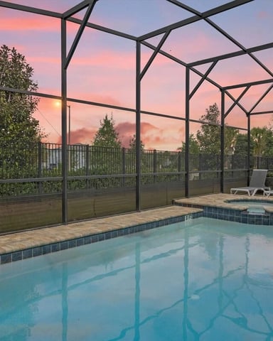 Screened private pool and spa at a Solara Resort villa under a vivid pink and orange sunset sky