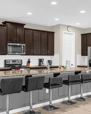 Spacious full kitchen in a Solara villa with dark wood cabinets, granite island, and bar stools