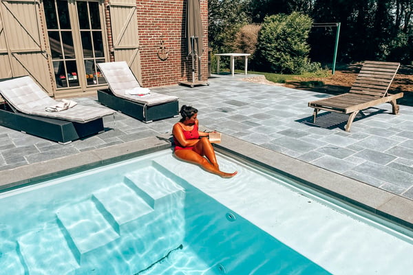 Guest relaxing poolside at a private vacation home, reading in the sun