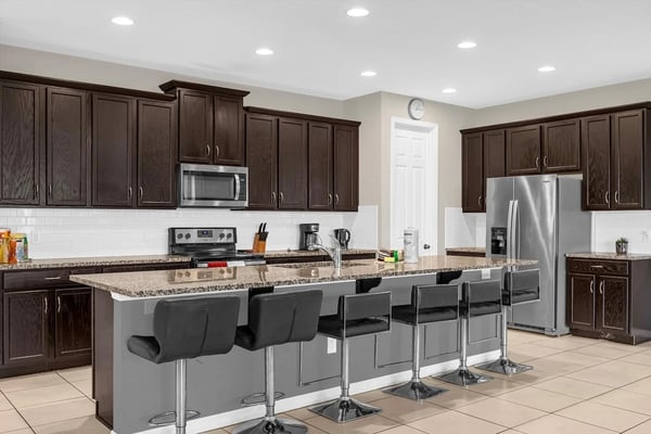 Modern kitchen with white cabinets, rattan pendant lights, and a large island