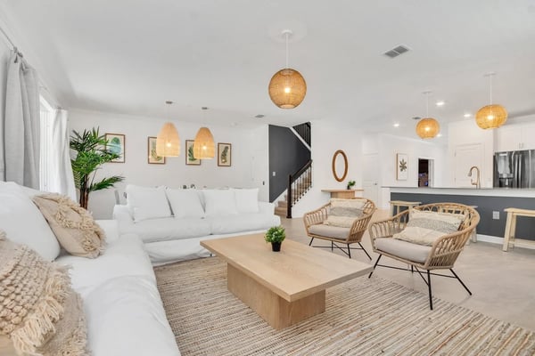 Bright open-plan living room with white sofa and rattan chairs, styled for a top-performing listing