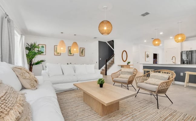 Bright open-plan living room with white sofa, rattan pendant lights, and natural-fibre rug in a Kissimmee villa